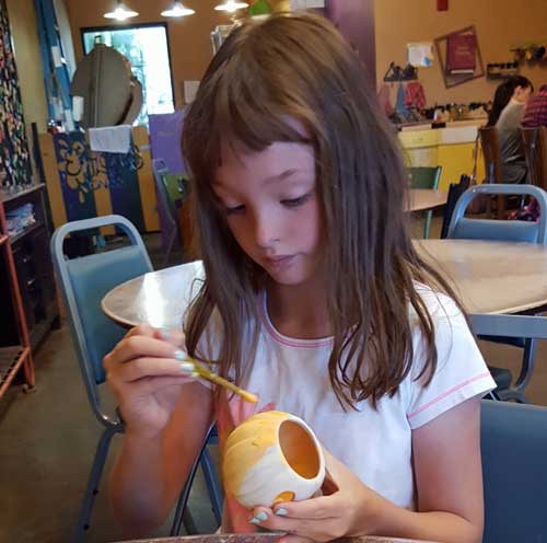 Chloe paints a clay pumpkin