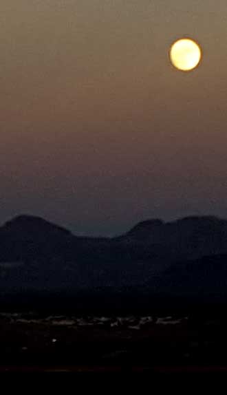 A full moon sits over Bullhead City and the mountains to the east. 